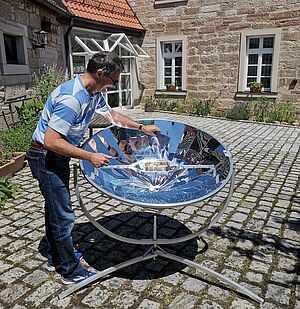 Person neben Parabol-Solarkocher